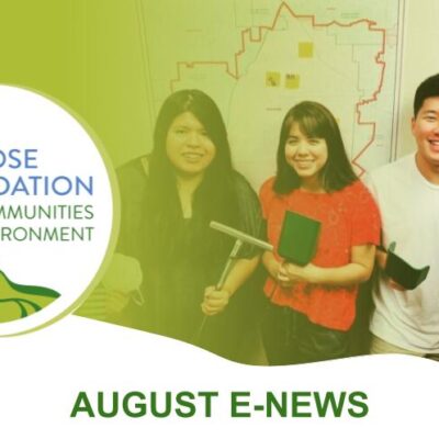 Four people are smiling and holding gardening tools indoors. To the left, there's a logo with a white rose and text that reads "Rose Foundation for Communities and the Environment." Below, green text reads "AUGUST E-NEWS.