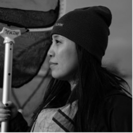 B&W profile photo of woman with black beanie and long dark hair.