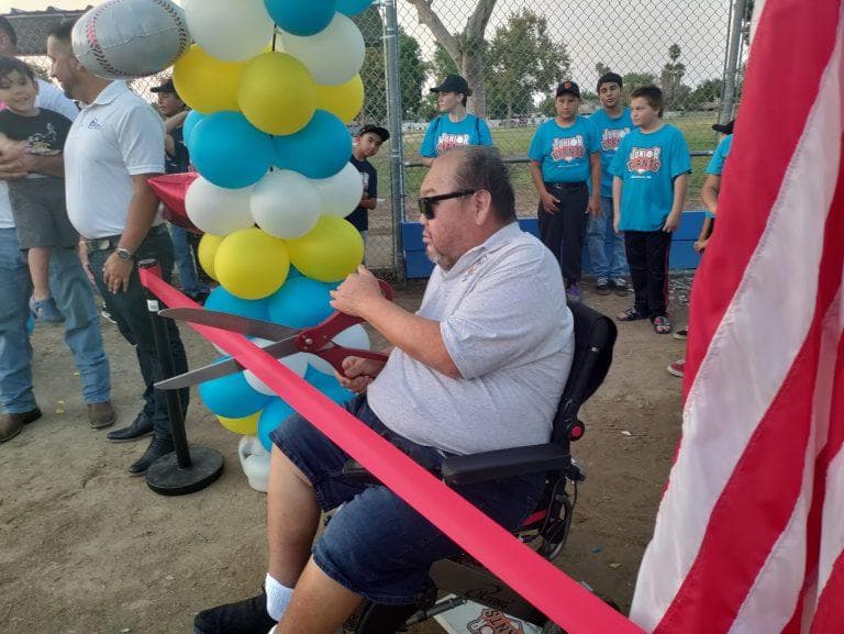 Jose Mireles cutting the ribbon for the grand reopening of 2 baseball fields that the committee helped remodel.