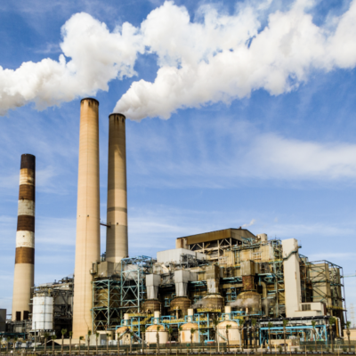 Industrial facility with four smoke stacks in front of a blue sky