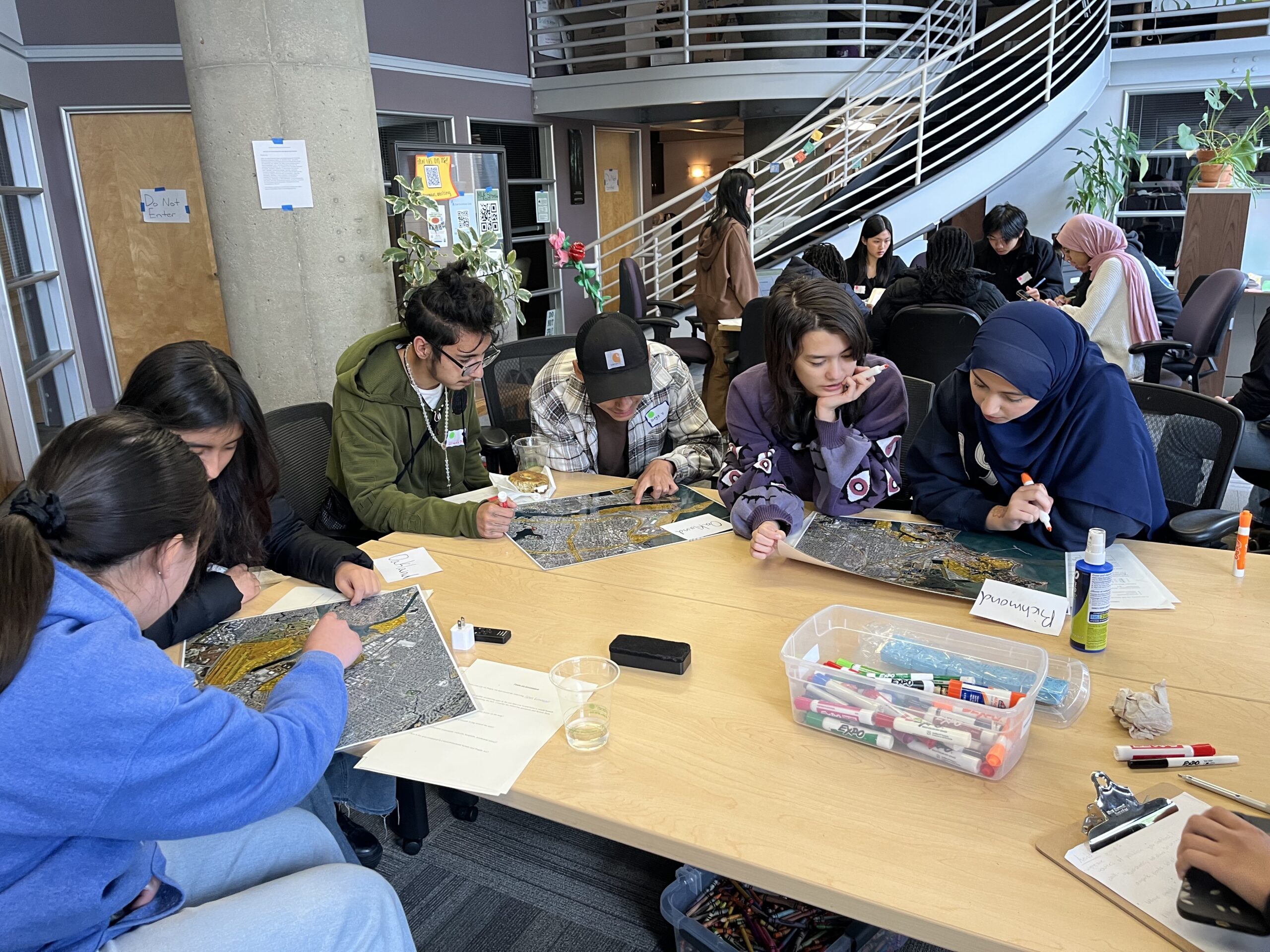 Youth at Air Monitoring Workshop pointing to maps of East Bay.
