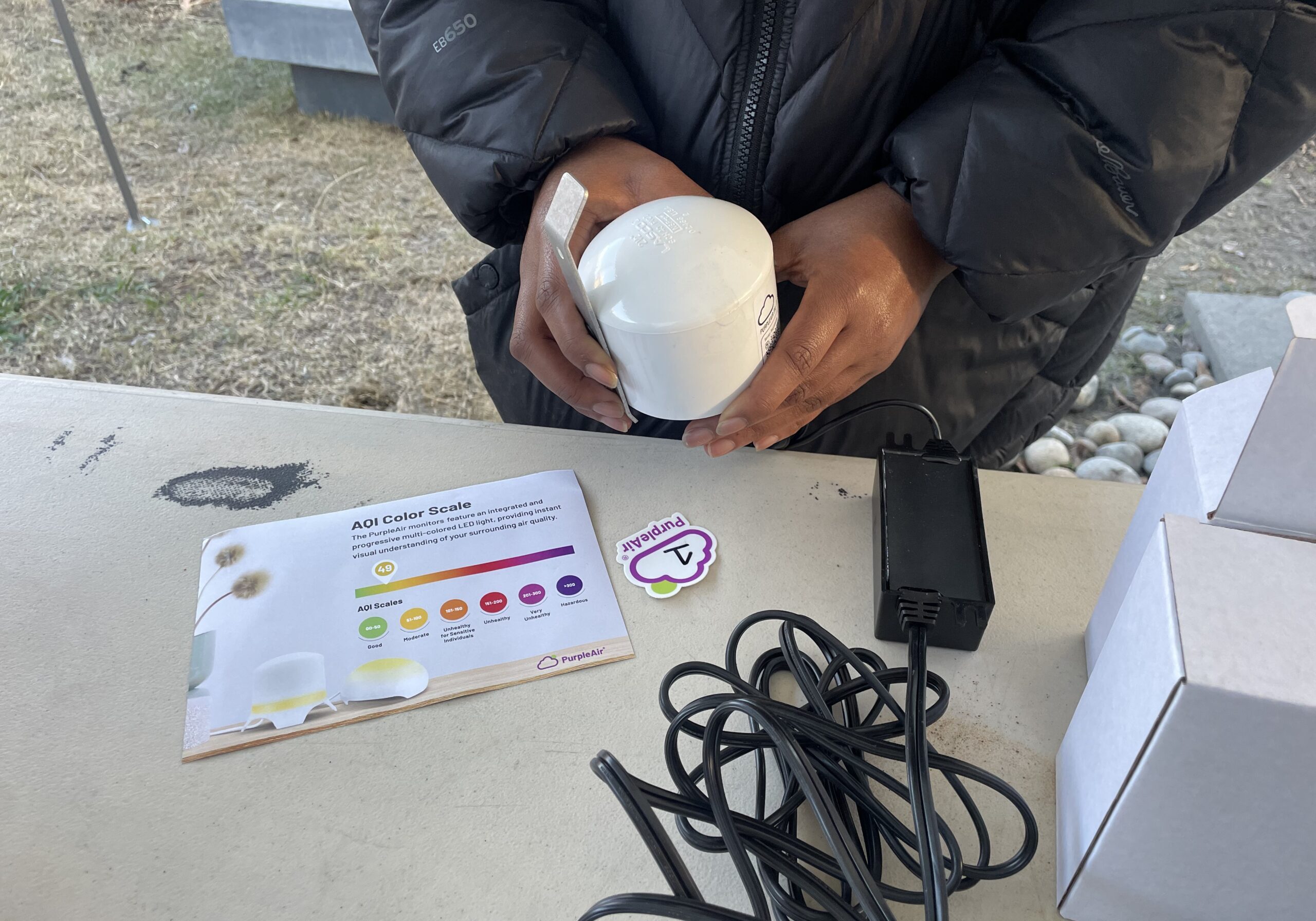 New Voices Staff holding PurpleAir Monitor.