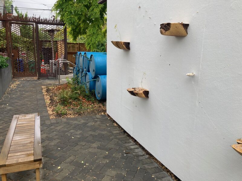 Recycled metal barrels and rustic log planters decorate the park area.